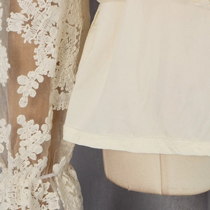 Détail de la broderie en dentelle florale et couture du tissu sur la blouse blanche