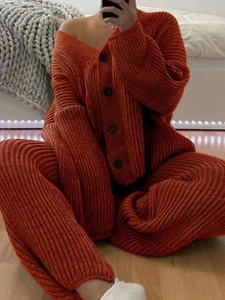 Detail view of orange-red chunky knit cardigan set with black buttons and ribbed texture