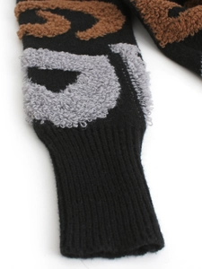 Détail de maille bouclée noire douce avec motifs jacquard marron et gris sur le cardigan