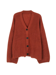 Detailed view of rust red chunky knit cardigan featuring large black buttons and V-neckline