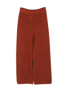 Detail of rust red knit wide-leg trousers with vertical texture and elastic waistband