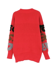 Détail du cardigan en maille rouge avec broderie de lettres texturées sur les manches