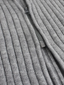 Detail shot of the vertical rib-knit texture and matching grey zipper on the cardigan