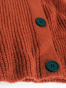Close-up of caramel knit cardigan with rib texture and large dark round buttons