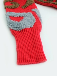 Détail des poignets côtelés sur cardigan en maille rouge avec motifs gris et bruns