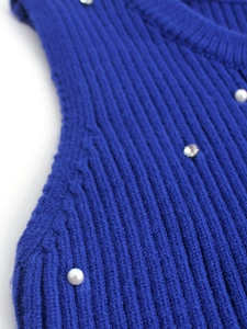 Detail of dark blue ribbed knit fabric with white pearls and sparkling rhinestones decoration