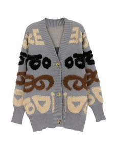 Détail d'un cardigan en maille grise avec motifs jacquard et boutons ambrés
