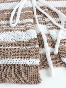 Dettaglio del cardigan in maglia a righe marroni e bianche con coulisse in tessuto spesso
