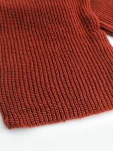 Close-up of brick red rib-knit fabric texture with high-quality wool blend detail