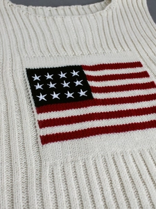 Close-up of cream knit sweater vest with vertical ribbing and USA flag pattern