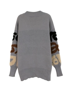 Détail d'un cardigan gris oversize avec motifs texturés et finitions en maille côtelée
