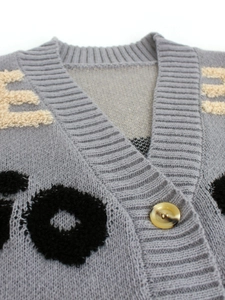Gros plan du cardigan gris en maille col V avec broderie de lettres et détail du bouton