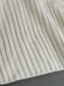 Close-up of cream knit sweater showing vertical ribbed texture and premium fabric details