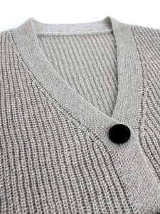 Detail of light gray knit cardigan featuring ribbed texture and a large matte black button