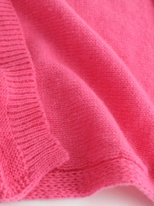 Close-up of pink knitted cardigan showing soft plush texture and ribbed cuff details