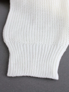 Close-up of white waffle knit sweater with ribbed cuffs and textured cotton fabric