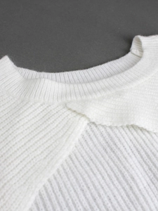Close-up of white ribbed knit sweater featuring a unique overlapping crew neckline