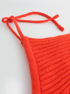Close-up of a bright red ribbed knit sleeveless top with delicate knotted shoulder straps