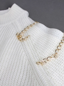 Macro detail of white ribbed knit sweater featuring chic gold metal chain link hardware