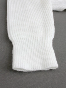 Detailed macro view of white ribbed knit fabric texture on a long sleeve pullover top