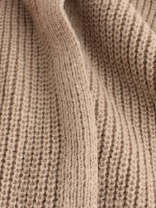 Close-up of thick beige ribbed knit fabric showing soft texture and premium material