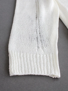 Détail de la manche en maille blanche avec motifs ajourés et poignet à côtes