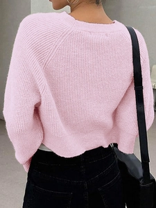 Back view of a cropped light pink chunky knit sweater with round neck and ribbed hem