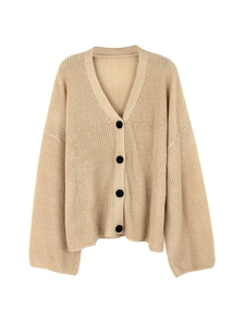 Detailed close-up of apricot knit cardigan featuring a V-neck and black contrast buttons