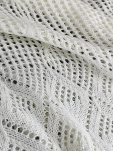 Gros plan sur le tissu au crochet blanc montrant les motifs ajourés et la texture