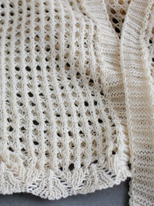 Close-up of cream open-knit crochet texture and diamond mesh detail on the cardigan