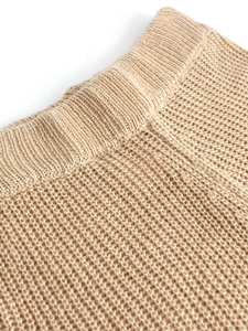 Detailed close-up of ribbed knit texture and waffle pattern on beige knitted cardigan