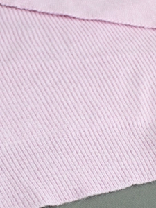 Close-up of light pink ribbed knit fabric texture on a long sleeve pullover top