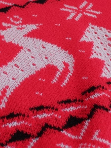 Gros plan sur tissu en maille rouge avec motifs jacquard de renne et flocon blanc