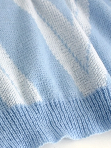 Close-up of soft light blue knit sweater fabric with ribbed hem detail and fine texture