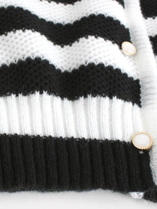 Close-up of black and white wavy stripes on knit cardigan with gold-edged pearl buttons