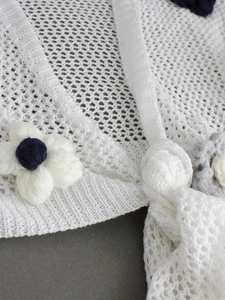 Detail of white crochet knit cardigan with 3D handmade floral embroidery and ribbed edges