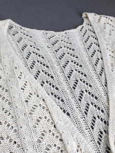Detailed macro view of ivory white pointelle knit cardigan with geometric crochet pattern