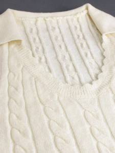 Gros plan d'un débardeur en maille torsadée crème avec un col polo élégant