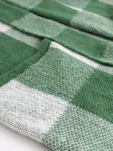 Detailed macro view of the soft knit texture on a green and white checkered cardigan