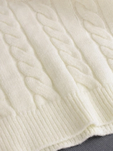 Détail macro du débardeur en maille torsadée blanc crème avec ourlet côtelé et doux