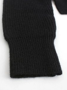 Detail of ribbed cuff on black knitted sweater showing soft textured fabric finish
