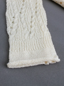 Cream knit cardigan with intricate cable patterns and textured tie-up detailing