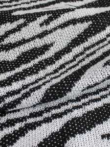 Detailed close-up of premium black and white zebra pattern knit fabric on summer dress