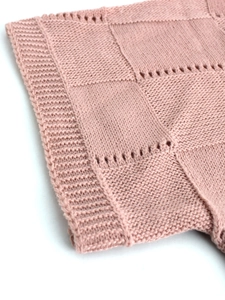 Close-up of pink knit fabric with hollow pointelle patterns and ribbed edges detail