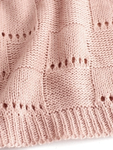 Detailed close-up of pink pointelle knit fabric with soft texture and ribbed hem detail