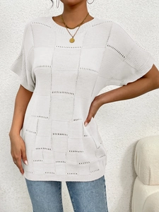 Close-up of white knitted short sleeve top with checkerboard pattern and hollow details