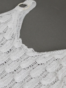 White sleeveless hollow-out knit sweater featuring intricate crochet patterns and ring buckle