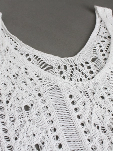 Detailed close-up of white crochet knit sleeveless dress with intricate hollow out patterns