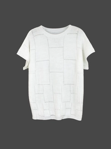 Detailed view of the white knit top featuring elegant geometric hollow-out patterns