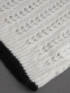 Top in maglia bianca lavorata all'uncinetto con bordo nero e trama a rombi